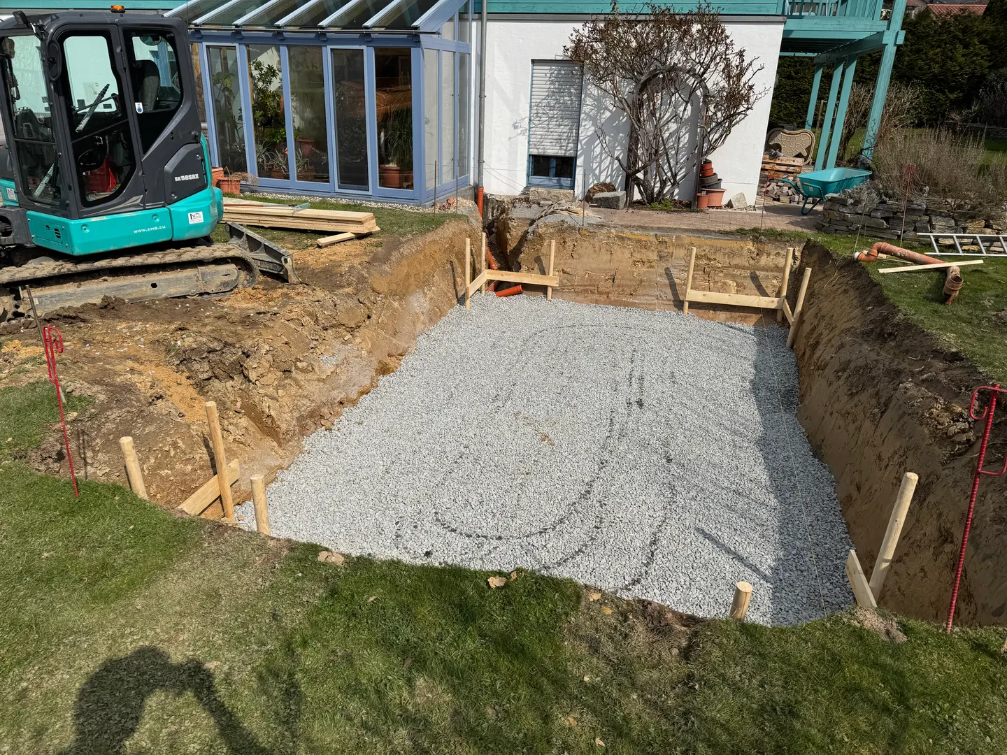 Baugrube mit Schotterschicht neben dem Haus.